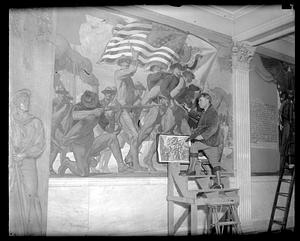A man stands on scaffolding in front of the Spanish-American War Memorial Mural, Massachusetts State House