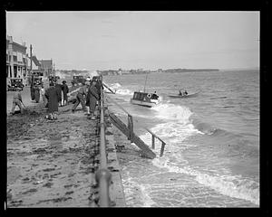 People by a beach with high surf, probably after a storm