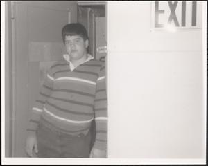 Boy in striped shirt standing next to an exit sign