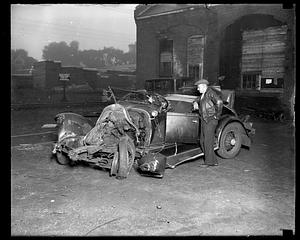 A man stands next to a damaged car