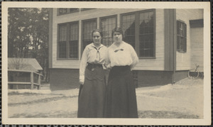Two women standing at side of former schoolhouse