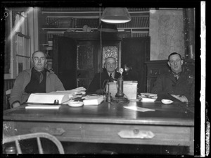 Three unidentified men seated at desk