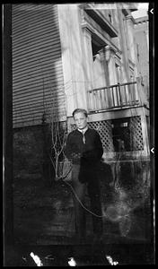 A young man stands in front of a house