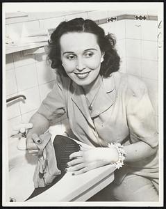 Mothers Feel at Home away from home when she carries one of these small-sized, plastic washboards on a trip, no doubt. Rita McAlpin demonstrates the new model at the Los Angeles meeting of the Inventors of America.