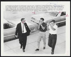 Deputy U.S. Marshal J. Clarence Burns (left) ushers two Ku Klux Klansmen Cecil Myers (dark shirt, C) and Joseph Sims to Bibb County jail, after trip from Athens, Ga., where they waived preliminary rights on federal charges, leaving the way open for prosecution under Georgia law for murder. Four Klansmen, including this pair, are charged with the shotgun slaying of Negro educator Lemuel Penn as he drove along a Georgia road with two companions returning from Army summer training at Fort Benning.