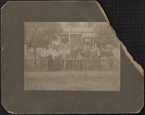 Multigenerational group in front of house with picket fence