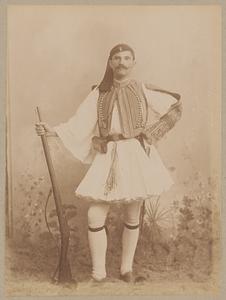 Studio portrait of man in traditional Greek dress holding a rifle