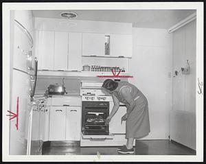 Kitchen Mechanics. Mrs. John Stamy Jr., checks on dinner cooking in the oven of the electric stove in the kitchen of the Stamy farm near Newville, Pa. Mrs. Stamy and her husband have electrified their farm to make it attractive to their four young sons as they grow up. Dozens of electrical appliances make work easy in the kitchen. Throughout the house more than 54 circuits handle current for all sorts of appliances. Electrical outlets are placed so that at no point is one more than six feet away, for convenient use.