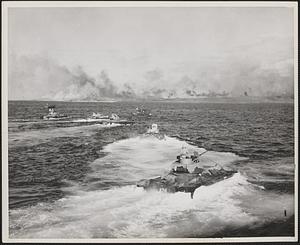 A wave of Marine LVT's, (Landing Vehicle Tracked) churn up white wakes as they leave the line of departure and head for the smoke shrouded beach of Iwo Jima