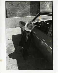 Portrait of young girl leaning against a car