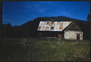 Small building in meadow with hill in background, British Columbia
