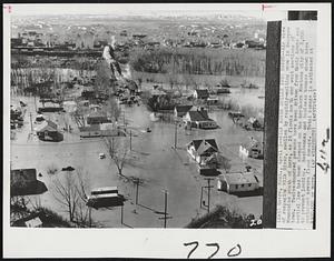 Milk River Spills Into Havre--Air view of rampaging Milk River, swollen by rapidly-melting snow in Bearpaw Mountains south of here, as it floods north and west sections of town. Twelve-hundred persons have been driven from their homes and martial law has been clamped on the northern Montana city of 8,000 to prevent looting. Residence and business houses shown here sustained severe flood damage. Total damage is estimated at $300,000 or more.