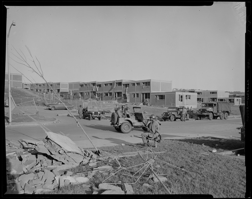 Military personnel and trucks near tornado debris