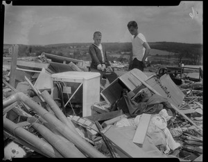 Two boys discussing items at a wreckage site