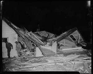 Two men walking away from the wreckage left by a house's collapsed roof