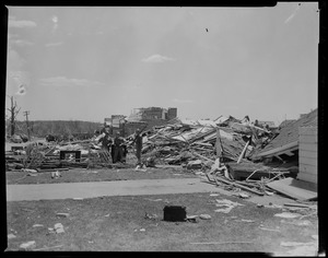 Group of military personnel standing next to debris left by tornado