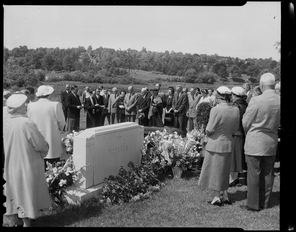 Mourners gathered at gravesite with headstone reading "Roberts"