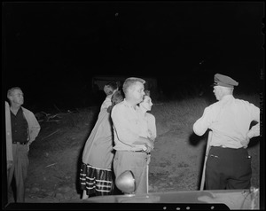 Group of people, including a police officer, talking in a field
