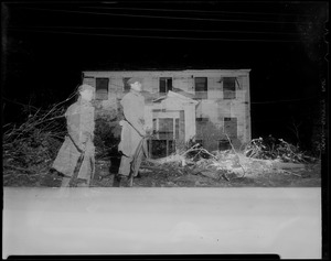 Two military men, downed trees, and building damaged by tornado