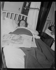 Woman lying in bed with a newspaper