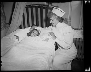 Nurse attending to a child in bed