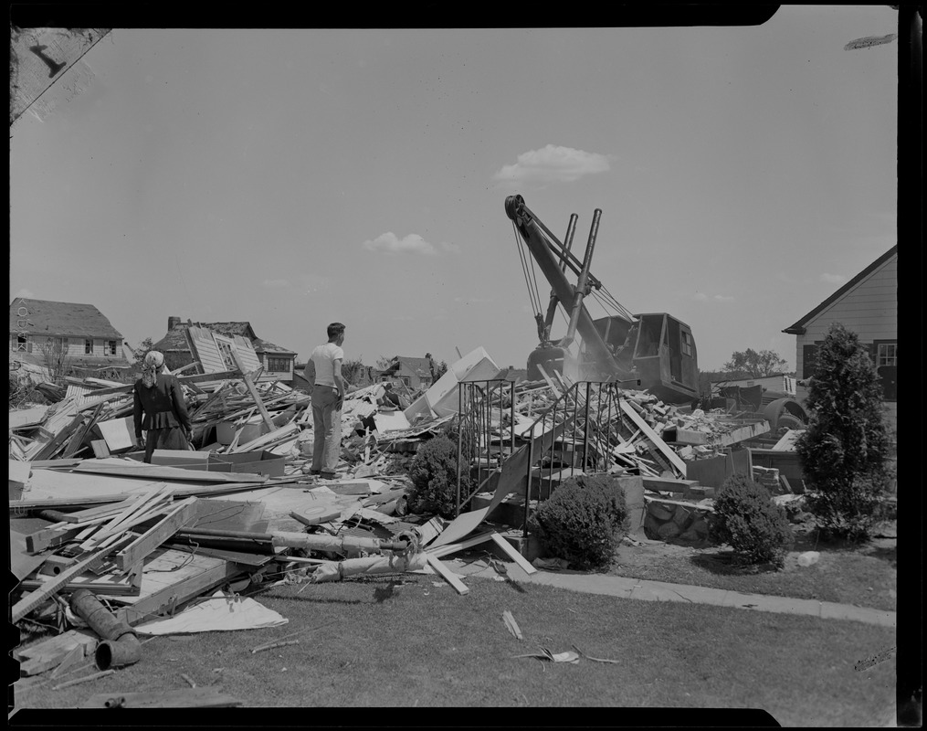 Man and woman watching as a crane moves wreckage from tornado - Digital ...