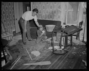 Man and young boy going through wreckage from tornado in room of house