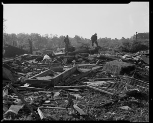 Military men standing on wreckage left by tornado
