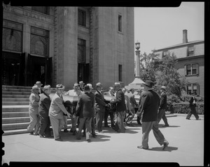 Pallbearers carrying three coffins out of church