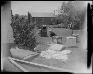Boy sitting in yard near trees and home furnishings damaged by tornado