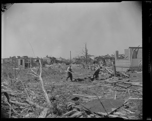 Two men carrying an object through wreckage from tornado