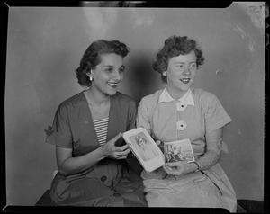 Two women posing with photographs