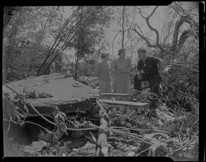 Three people talking, one wearing a possible American Red Cross uniform, amid debris from tornado