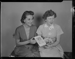 Two women posing with photographs