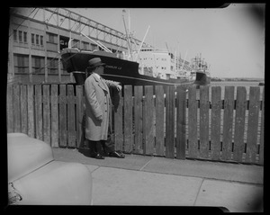 Matt Cvetic leaning on fence and looking out over Boston waterfront and Charles LD ship