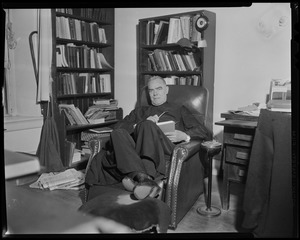 Fr. Joseph T. O'Callahan seated in chair, in front of bookcase
