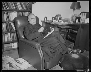 Fr. Joseph T. O'Callahan seated in chair, with feet on ottoman