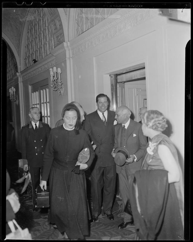 Jawaharlal Nehru walking into room with people holding hat