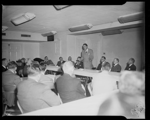 Billy Graham standing behind table, addressing the room