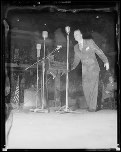 Billy Graham standing on stage behind podium and microphones