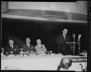 Lt. Gov. Robert Murphy speaking at podium with President of the Western Mass. Safety Council Lincoln Crosby, William Randolph Hearst, Jr., and president of the Mass. Safety Council Charles L. O'Reilly seated at table at Governor's traffic safety luncheon