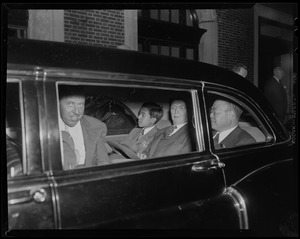 Crown Prince Akihito seated with three other men in the backseat of a vehicle