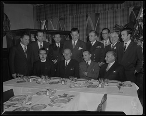 Prince George seated at dining table, with other men sitting and standing around him