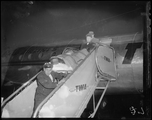 Princess Marie in a stretcher, being carried off of a TWA plane