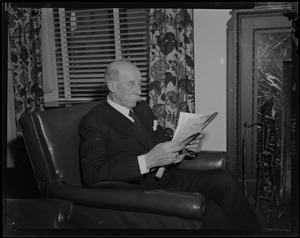 Prince George seated, reading newspaper