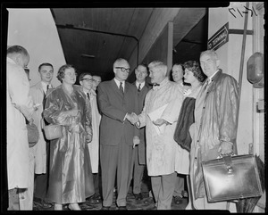 Sen. Barry Goldwater shaking hands with man, surrounded by crowd at airport