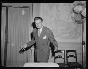 Billy Graham standing next to two chairs and fan