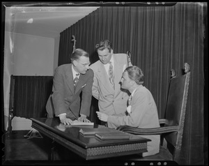 Billy Graham seated, in discussion with two men