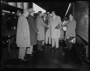 Billy Graham with group of men on train platform, shaking hands