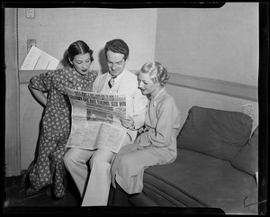 Fred Waring and two women looking at issue of Boston American newspaper with headline "Cronin Breaks Thumb, Sox Win"